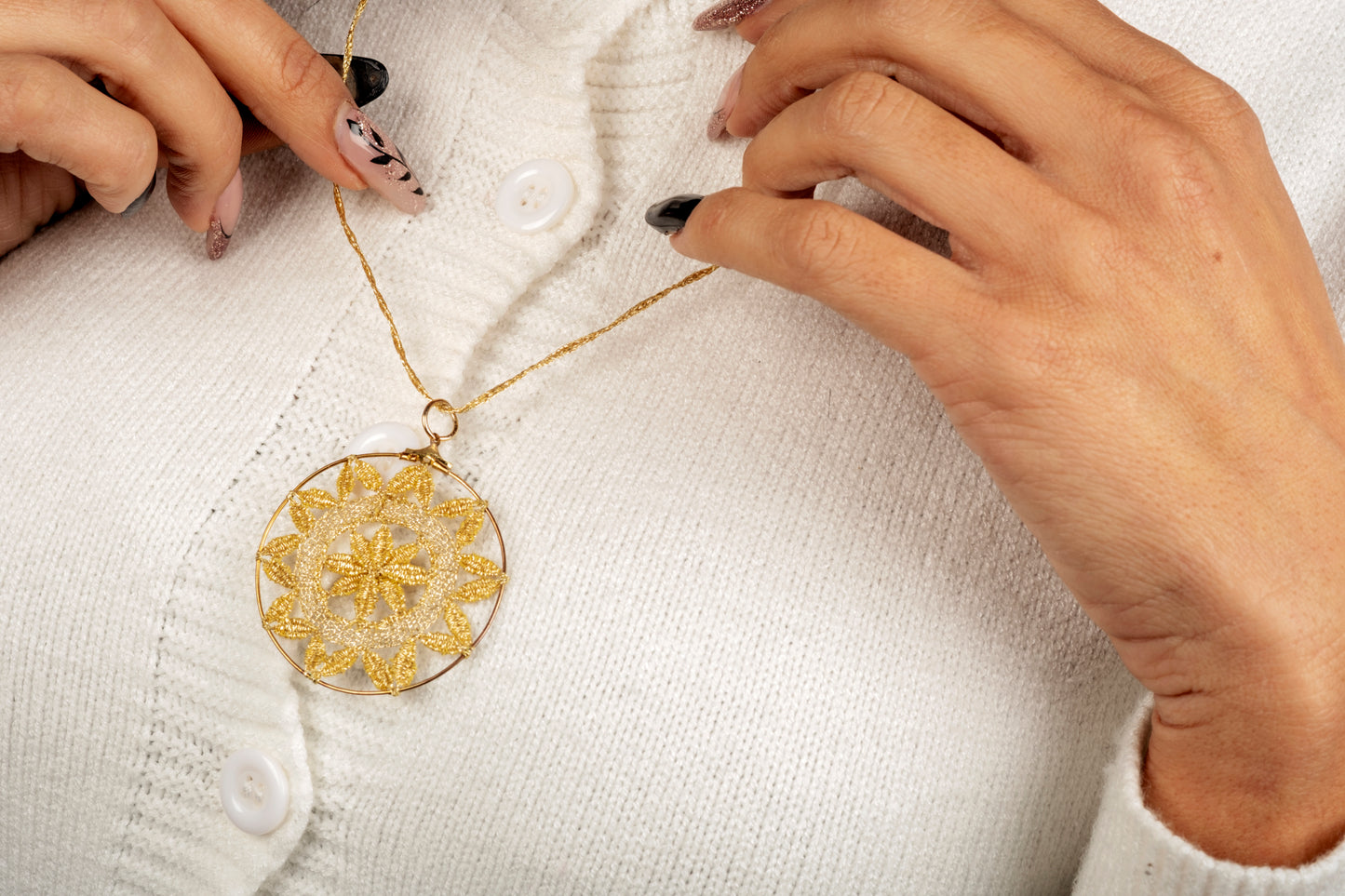 Bobbin lace pendant in metallic gold with a sparkling detail